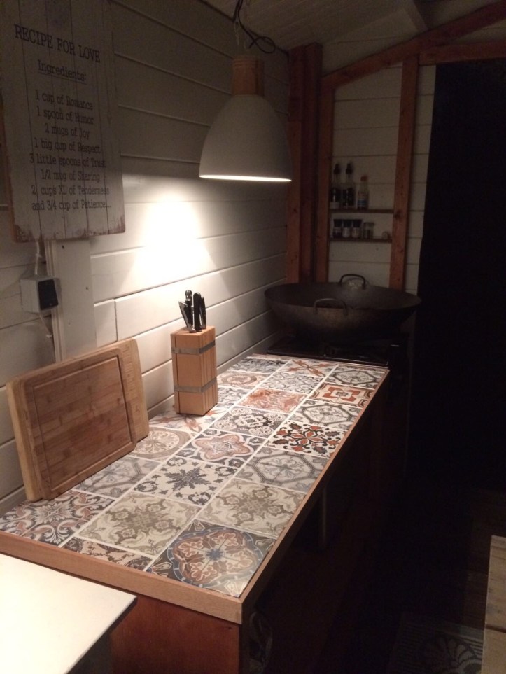 Foto bij avond van het aanrecht met licht er boven in de hut